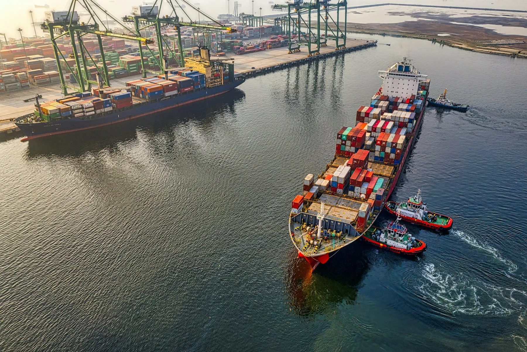 Container ship entering a port with tugboats