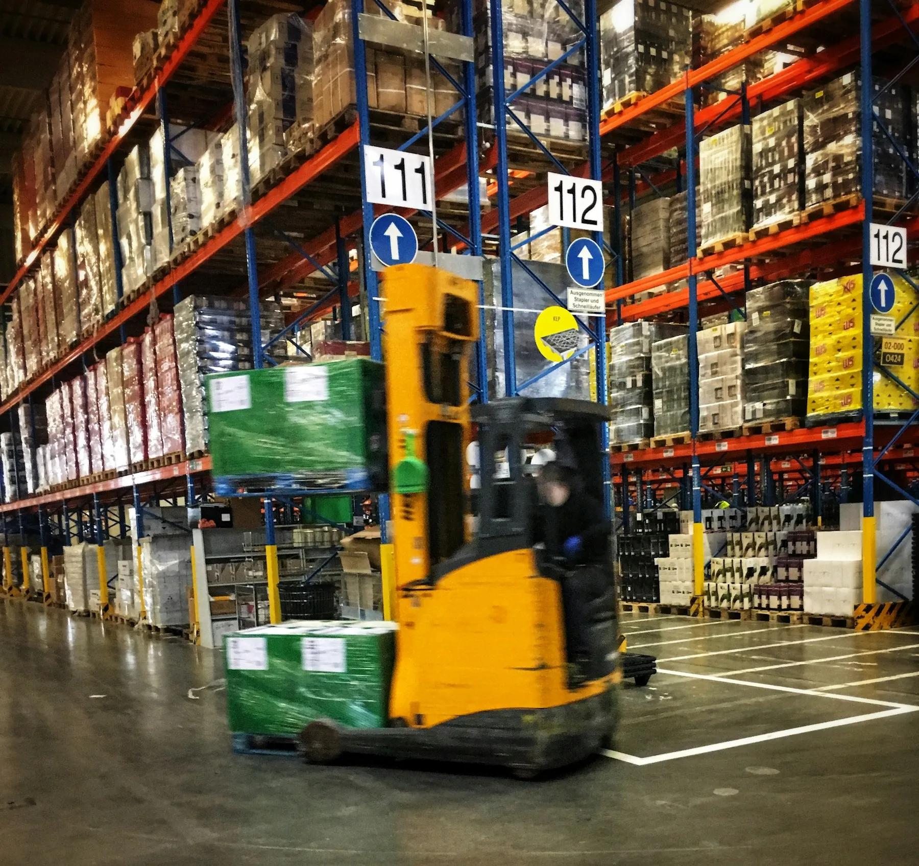 Forklift moving through a warehouse with stocked pallet racks